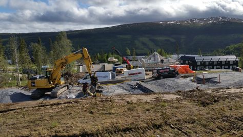 Byggarbetsplats, vita bilar, vitt släp, gul grävmaskin